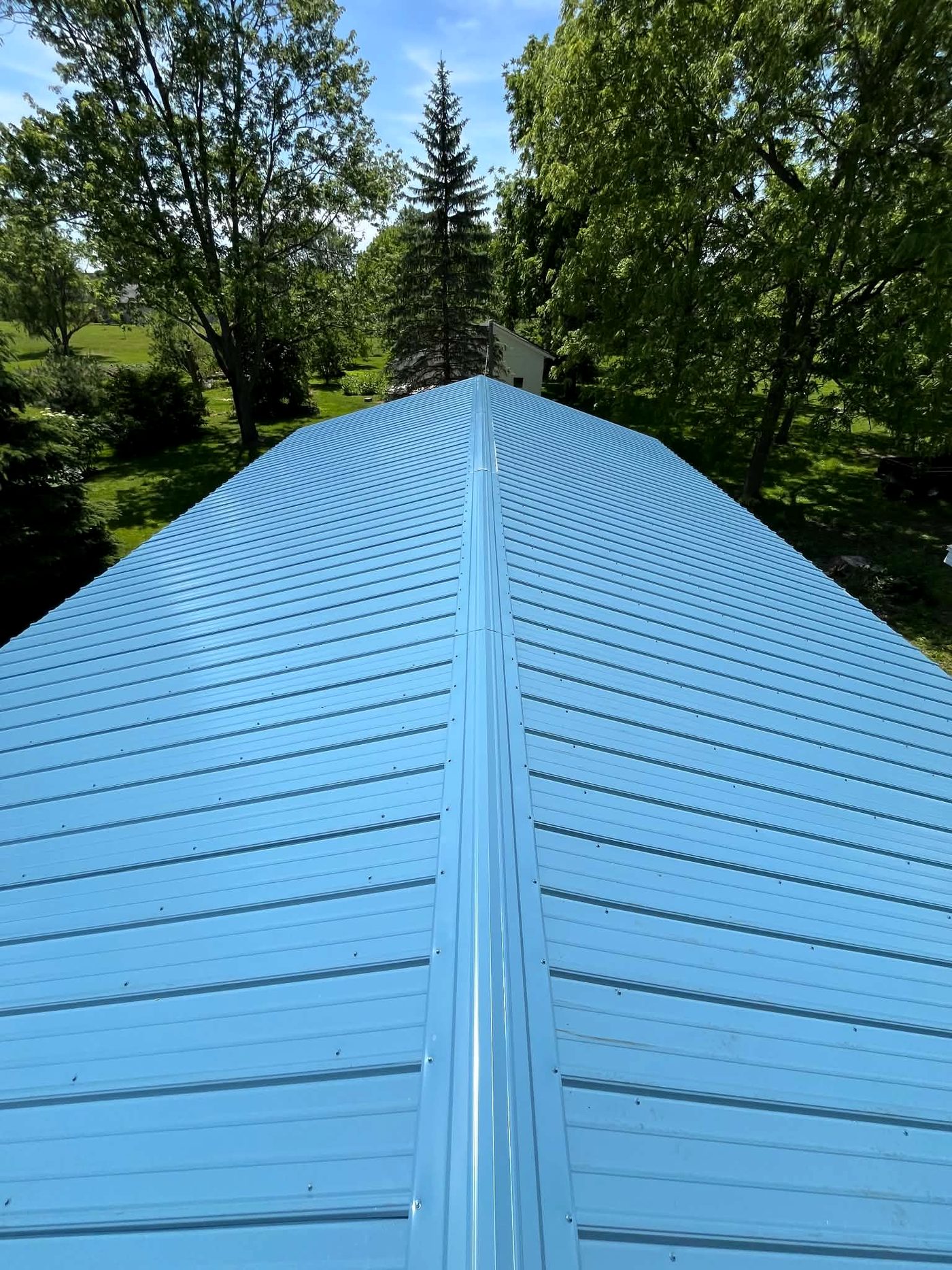 A finished blue standing seam metal roof seen along the ridge line